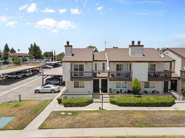 9100 Acacia Ave Unit 6, Fontana, CA 92335 - view of front facade featuring a chimney, covered and uncovered parking, stucco siding, a front lawn, and french doors