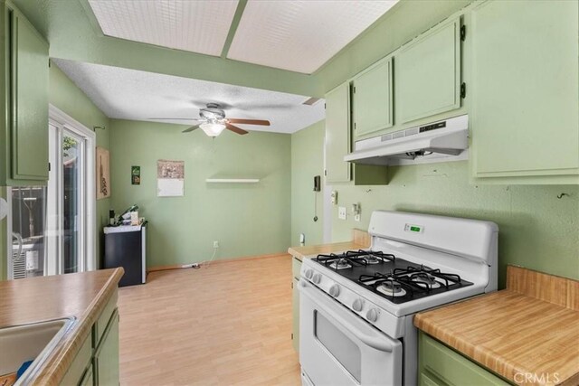 9100 Acacia Ave Unit 6, Fontana, CA 92335 - kitchen with white gas range oven, under cabinet range hood, green cabinetry, ceiling fan, and light wood-style flooring