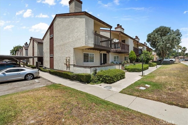 9100 Acacia Ave Unit 6, Fontana, CA 92335 - view of property exterior with a balcony, stucco siding, a yard, a residential view, and a parking lot