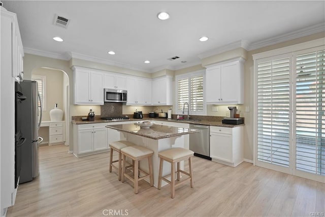 29851 Fox Creek Dr, Menifee, CA 92586 - kitchen featuring appliances with stainless steel finishes, arched walkways, light wood-style flooring, white cabinets, and recessed lighting