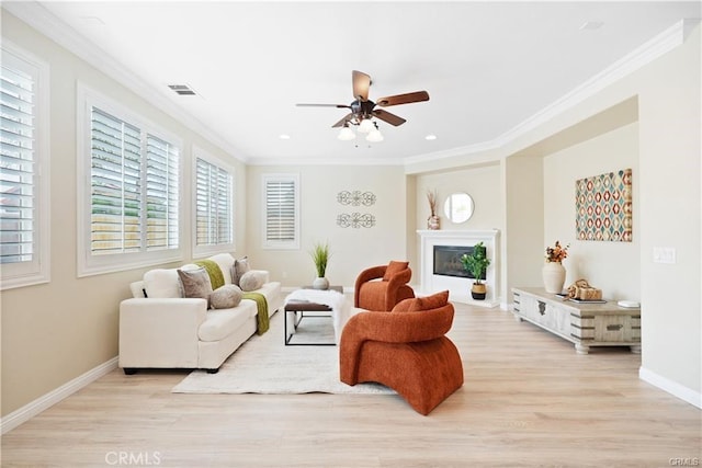 29851 Fox Creek Dr, Menifee, CA 92586 - living room with a ceiling fan, light wood-style floors, ornamental molding, a glass covered fireplace, and healthy amount of natural light