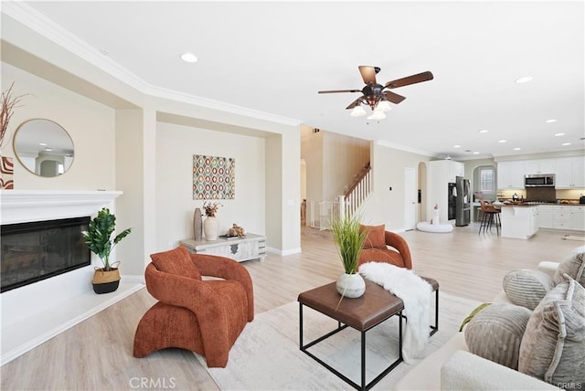 29851 Fox Creek Dr, Menifee, CA 92586 - living area with ornamental molding, stairs, light wood-type flooring, a glass covered fireplace, and recessed lighting