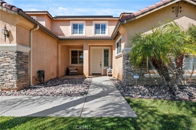29851 Fox Creek Dr, Menifee, CA 92586 - doorway to property featuring stucco siding, roof mounted solar panels, a tile roof, and stone siding