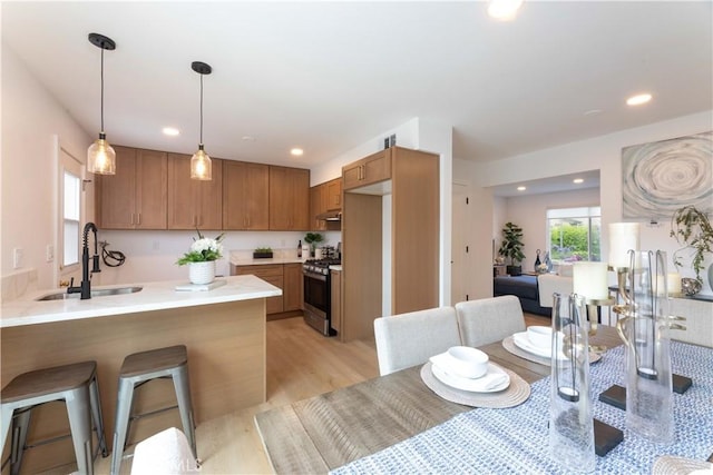 16509 Caballero Ln Unit 30B, Huntington Beach, CA 92649 - kitchen with stainless steel range with gas cooktop, a peninsula, light wood-style flooring, a breakfast bar area, and light countertops