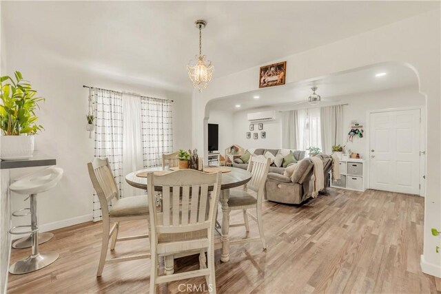 764 W 107th St, Los Angeles, CA 90044 - dining room with arched walkways, light wood-style floors, a wall unit AC, and a ceiling fan