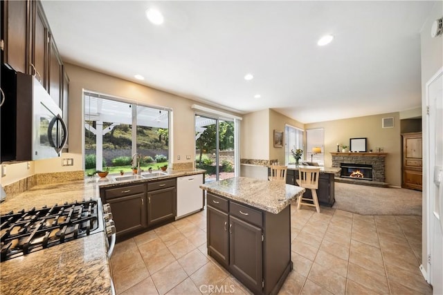 27628 Deerfield Ln, Valencia, CA 91354 - kitchen featuring dishwasher, gas range oven, a fireplace, light stone counters, and recessed lighting
