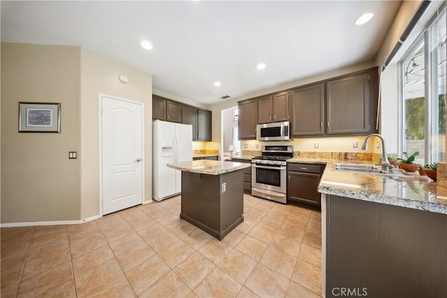 27628 Deerfield Ln, Valencia, CA 91354 - kitchen with appliances with stainless steel finishes, light stone countertops, a center island, light tile patterned flooring, and dark brown cabinets
