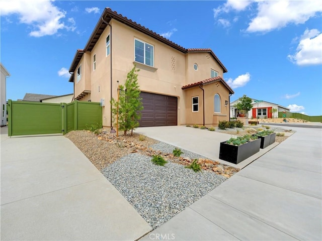 17151 Kent St, Hesperia, CA 92345 - mediterranean / spanish-style house with a garage, driveway, stucco siding, a tiled roof, and a gate