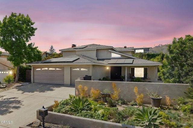 2325 Parkway Dr, Camarillo, CA 93010 - view of front facade featuring driveway, solar panels, an attached garage, stucco siding, and a chimney