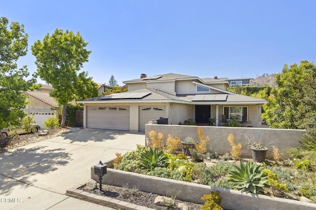 2325 Parkway Dr, Camarillo, CA 93010 - view of front of home featuring an attached garage, concrete driveway, stucco siding, roof mounted solar panels, and a chimney