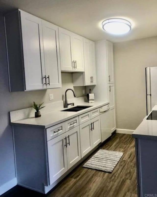 2330 Hosp Way Unit 303, Carlsbad, CA 92008 - kitchen with white dishwasher, freestanding refrigerator, dark wood finished floors, light countertops, and white cabinets