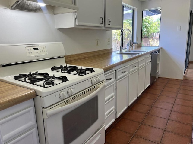1404 Lombard St, Vista, CA 92084 - kitchen with white gas stove, range hood, dishwasher, dark tile patterned flooring, and white cabinets