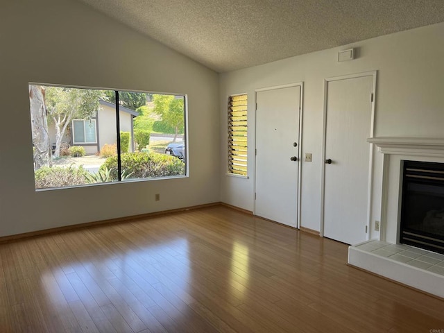 1404 Lombard St, Vista, CA 92084 - unfurnished living room featuring a tiled fireplace, a textured ceiling, lofted ceiling, and wood finished floors