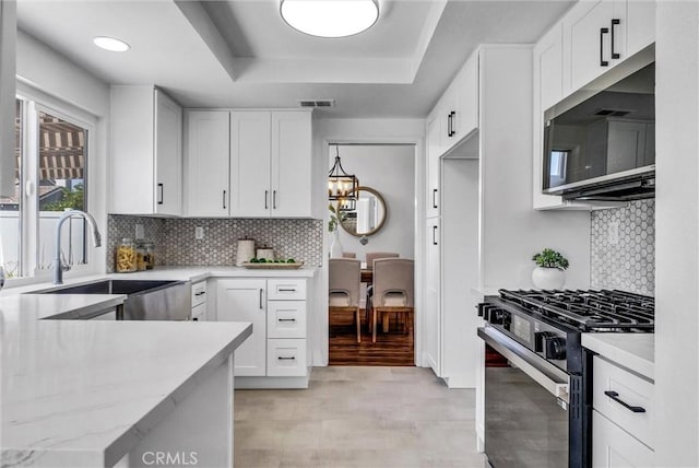 1251 Mayfair Dr, Corona, CA 92882 - kitchen featuring gas range, stainless steel microwave, a raised ceiling, backsplash, and white cabinetry