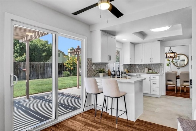 1251 Mayfair Dr, Corona, CA 92882 - kitchen featuring decorative backsplash, white cabinetry, a peninsula, and light countertops