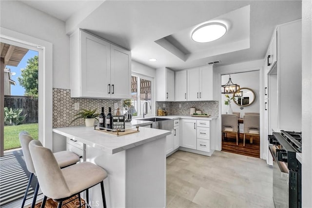 1251 Mayfair Dr, Corona, CA 92882 - kitchen with gas stove, a tray ceiling, a peninsula, and white cabinetry