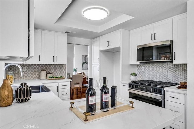 1251 Mayfair Dr, Corona, CA 92882 - kitchen featuring appliances with stainless steel finishes, a tray ceiling, white cabinets, and backsplash