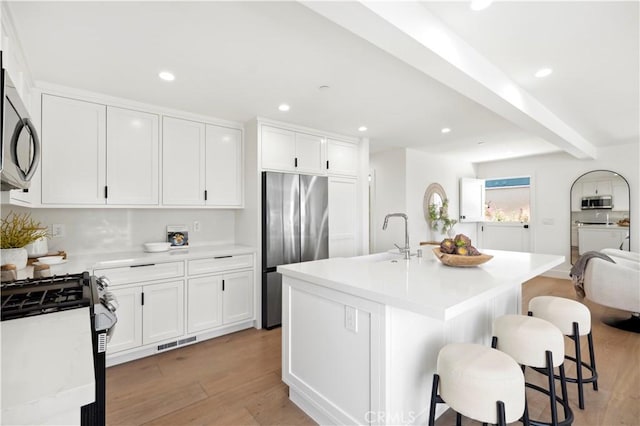 246 Fairview St, Laguna Beach, CA 92651 - kitchen with appliances with stainless steel finishes, light wood-type flooring, light countertops, a breakfast bar area, and white cabinets