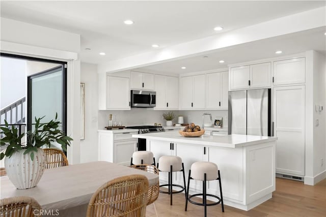 246 Fairview St, Laguna Beach, CA 92651 - kitchen with stainless steel appliances, a kitchen island, white cabinetry, light wood-style flooring, and recessed lighting