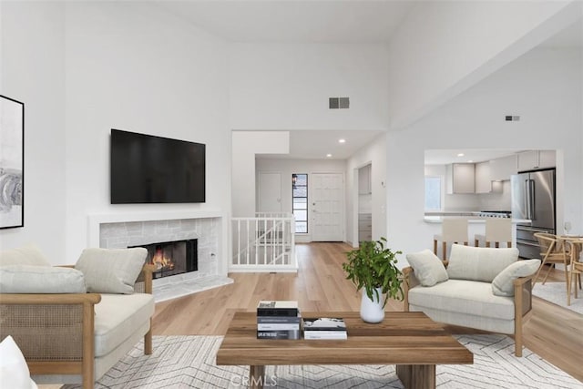 24616 Polaris Dr Unit 272, Dana Point, CA 92629 - living room featuring light wood finished floors, a towering ceiling, and a warm lit fireplace