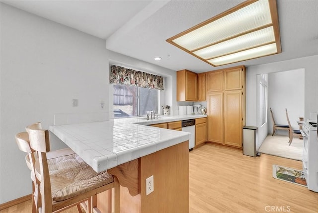 16737 Windcrest Dr, Fontana, CA 92337 - kitchen featuring dishwasher, a peninsula, light wood-style floors, tile countertops, and a kitchen breakfast bar