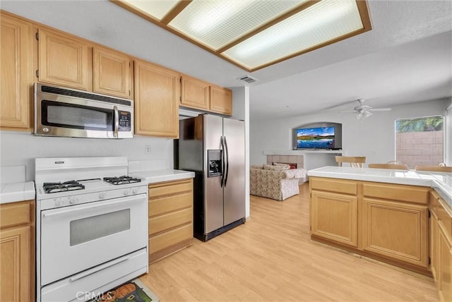 16737 Windcrest Dr, Fontana, CA 92337 - kitchen featuring appliances with stainless steel finishes, light wood finished floors, open floor plan, and tile counters