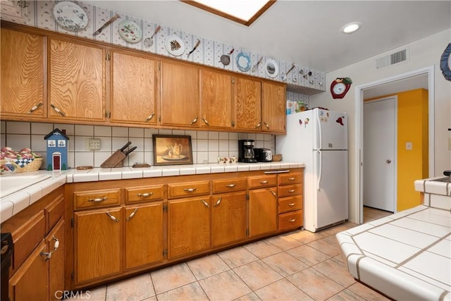 28839 Carmel Rd, Menifee, CA 92586 - kitchen with freestanding refrigerator, brown cabinets, tasteful backsplash, light tile patterned floors, and recessed lighting