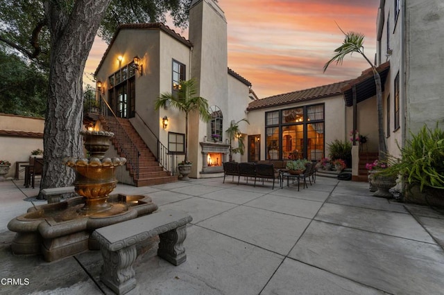 1205 Linda Vista Ave, Pasadena, CA 91103 - back of house at dusk with a tile roof, stucco siding, a chimney, a patio, and outdoor lounge area