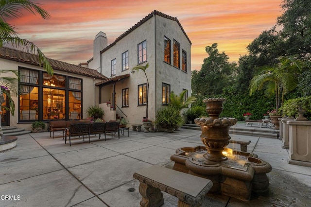 1205 Linda Vista Ave, Pasadena, CA 91103 - back of property at dusk with a patio, stucco siding, a chimney, an outdoor living space, and a tiled roof