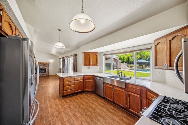 32618 Durango Ct, Wildomar, CA 92595 - kitchen featuring appliances with stainless steel finishes, a peninsula, vaulted ceiling, plenty of natural light, and brown cabinetry