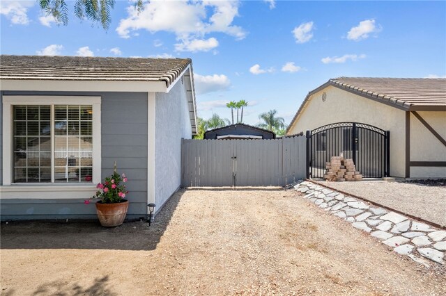 32618 Durango Ct, Wildomar, CA 92595 - view of home's exterior with a gate, stucco siding, a tile roof, and dirt driveway