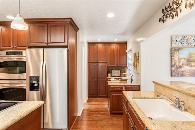 3191 Woodstock Rd, Rossmoor, CA 90720 - kitchen with appliances with stainless steel finishes, wood finished floors, decorative light fixtures, light stone countertops, and recessed lighting