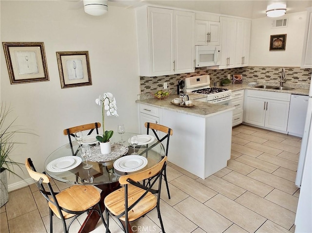 16573 Pescado Ln Unit 3A, Huntington Beach, CA 92649 - kitchen featuring white appliances, tasteful backsplash, a peninsula, white cabinets, and light tile patterned flooring