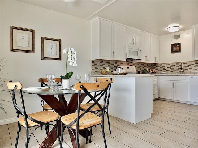 16573 Pescado Ln Unit 3A, Huntington Beach, CA 92649 - kitchen featuring white appliances, tasteful backsplash, white cabinetry, and a peninsula