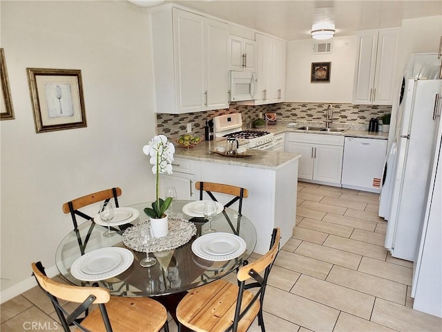 16573 Pescado Ln Unit 3A, Huntington Beach, CA 92649 - kitchen with white appliances, backsplash, white cabinetry, a peninsula, and light tile patterned floors