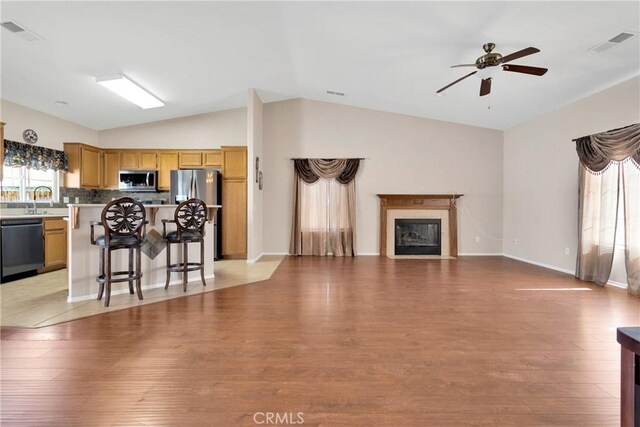 16029 Carmelia Dr, Victorville, CA 92394 - kitchen featuring stainless steel appliances, lofted ceiling, light wood-style flooring, open floor plan, and a glass covered fireplace