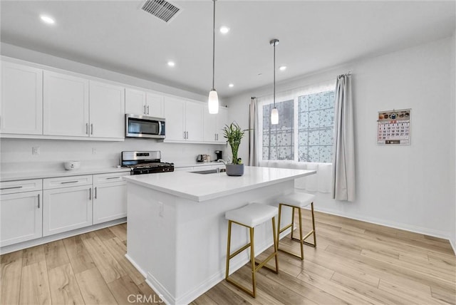 34410 Granite Rd, Yucaipa, CA 92399 - kitchen featuring appliances with stainless steel finishes, light wood-style floors, white cabinetry, an island with sink, and recessed lighting