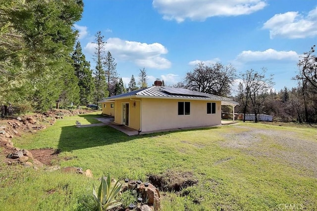 13001 Yuba Nevada Rd, Dobbins, CA 95935 - view of side of property featuring a standing seam roof, stucco siding, solar panels, a metal roof, and a chimney