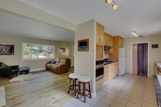 13001 Yuba Nevada Rd, Dobbins, CA 95935 - kitchen with stainless steel oven, under cabinet range hood, open floor plan, freestanding refrigerator, and gas stovetop