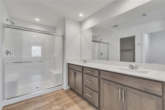 29812 Juniper Ct, Menifee, CA 92584 - bathroom featuring a shower stall, double vanity, wood finished floors, a walk in closet, and recessed lighting