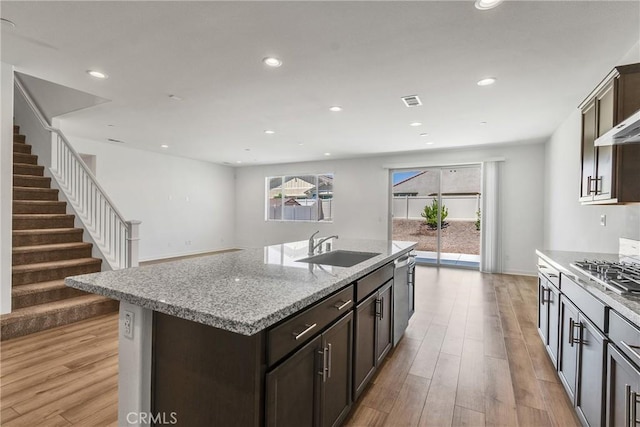 29812 Juniper Ct, Menifee, CA 92584 - kitchen with stainless steel gas stovetop, light wood-type flooring, recessed lighting, dark brown cabinetry, and light stone counters