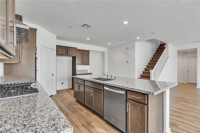29812 Juniper Ct, Menifee, CA 92584 - kitchen featuring appliances with stainless steel finishes, light wood finished floors, recessed lighting, a center island with sink, and light stone counters