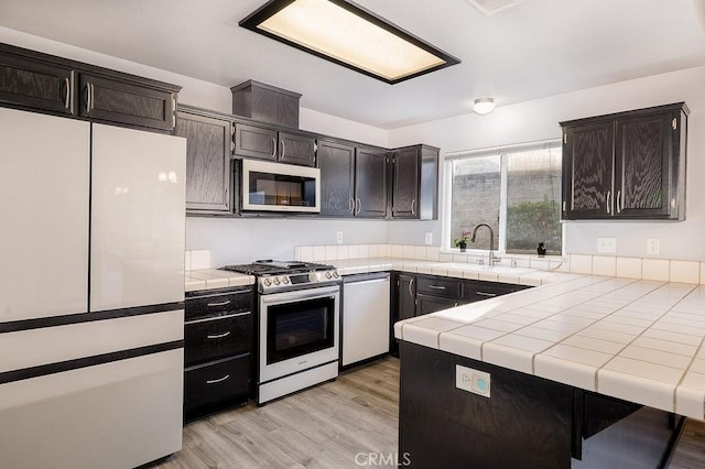 1085 Admiral Ln, Chico, CA 95973 - kitchen with white appliances, tile countertops, light wood finished floors, and a peninsula