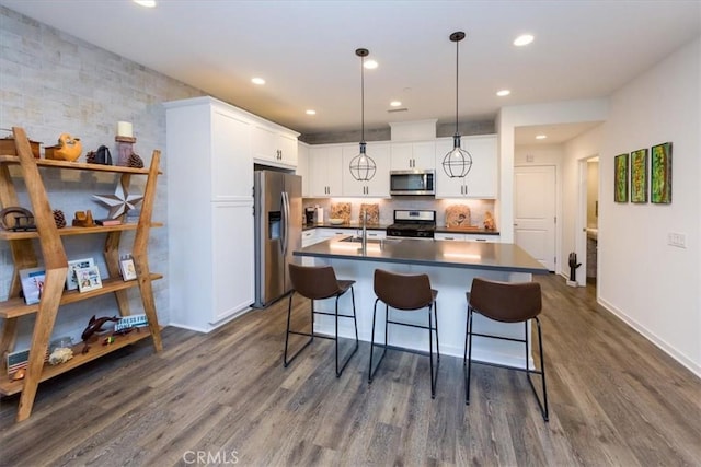 28606 Jardineras Dr, Valencia, CA 91354 - kitchen with stainless steel appliances, dark wood finished floors, white cabinetry, a breakfast bar area, and dark countertops