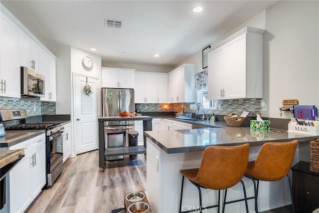 7002 Alice St, Highland, CA 92346 - kitchen featuring appliances with stainless steel finishes, tasteful backsplash, recessed lighting, white cabinetry, and a peninsula
