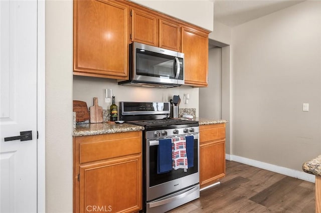 3094 Crooked Branch Way, San Jacinto, CA 92582 - kitchen featuring appliances with stainless steel finishes, dark wood finished floors, light stone counters, and brown cabinets