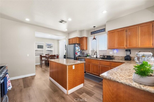 3094 Crooked Branch Way, San Jacinto, CA 92582 - kitchen with appliances with stainless steel finishes, wood finished floors, a kitchen island, brown cabinets, and recessed lighting