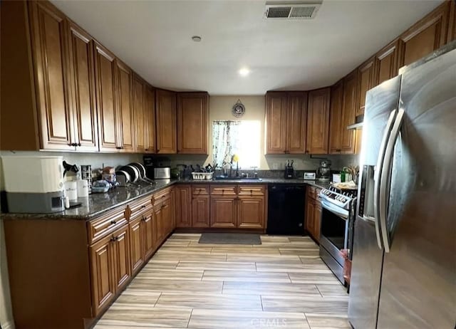 1019 W Arbutus St, Compton, CA 90220 - kitchen featuring appliances with stainless steel finishes, brown cabinetry, wood tiled floors, and dark stone countertops