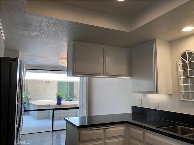 2545 Via Campesina Unit 102, Palos Verdes Estates, CA 90274 - kitchen with freestanding refrigerator, dark countertops, a peninsula, tile patterned floors, and white cabinetry