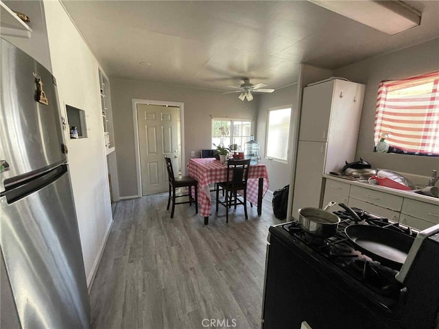 9051 Walker St, Cypress, CA 90630 - kitchen featuring freestanding refrigerator, black gas stove, a ceiling fan, wood finished floors, and white cabinetry